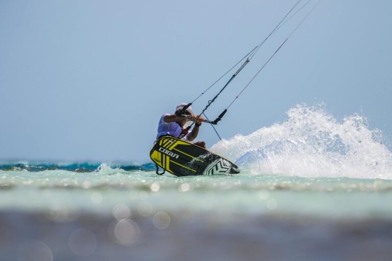A thrilling kitesurfing scene with splashing waves and clear blue sky, showcasing skill and adventure.
